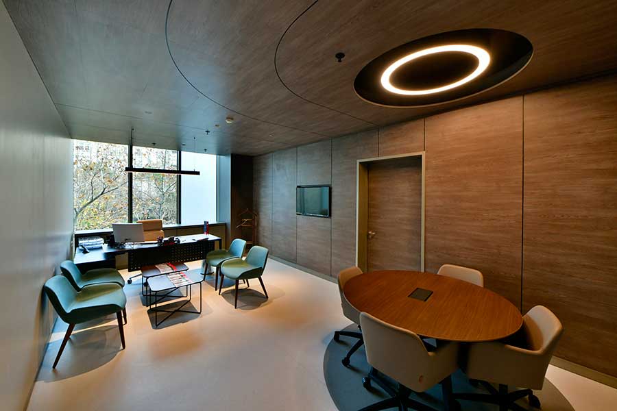 Consultation room where the specialist-signed plan is reviewed — wood panelling, ring light, round meeting table.