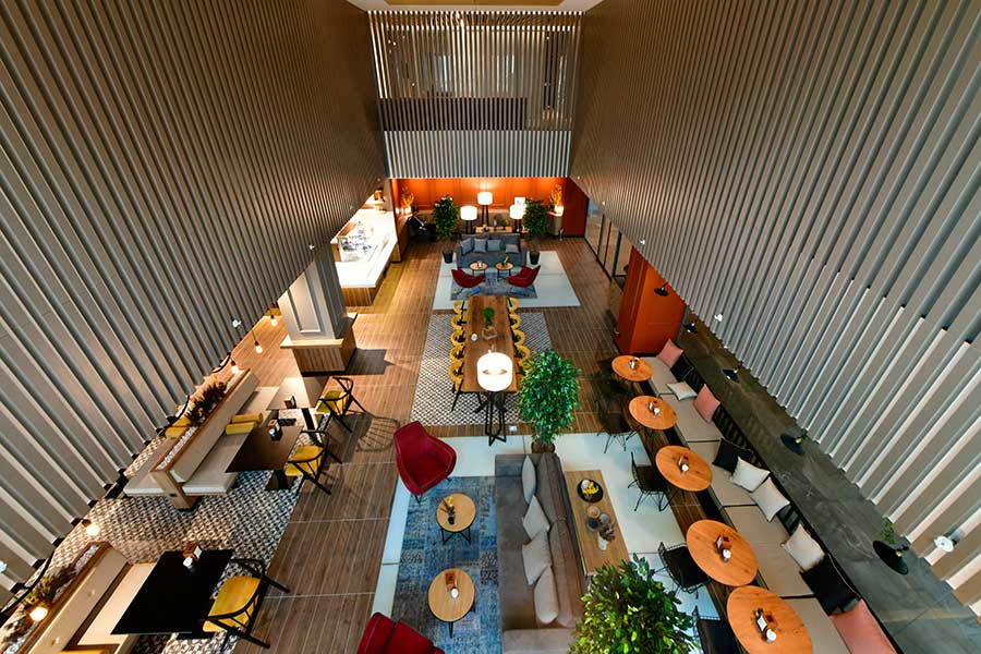 Ground-floor café and lounge at BHT Clinic Tema — wood-clad walls, café seating, plants, mid-morning daylight.